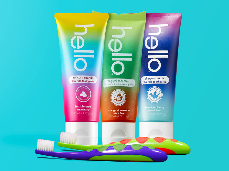 Hello Kids Fluoride Toothpaste Variety Pack – Unicorn Sparkle, Magical Mermaid, and Dragon Dazzle flavors with colorful toothbrushes on a bright blue background